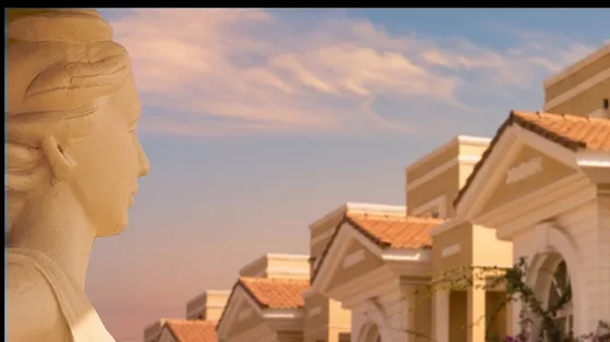 Sculpted stone figure with a row of pedimented villas behind at sunset
